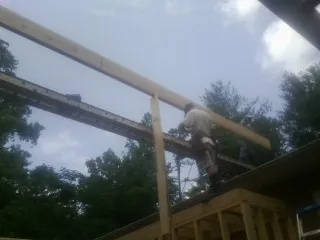 Carpenter setting a ridge beam over a new addition frame — Ice Dam Removal by Roofing Brothers in Center