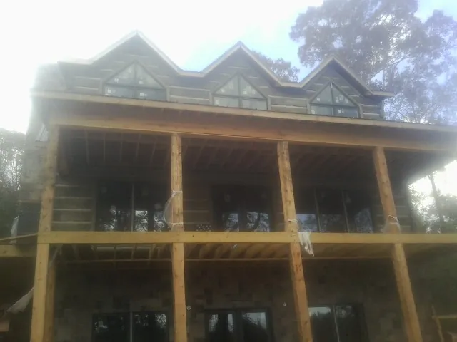 Dormers and porch framing on a large log home under construction — Roof Coating work by our crew in Center
