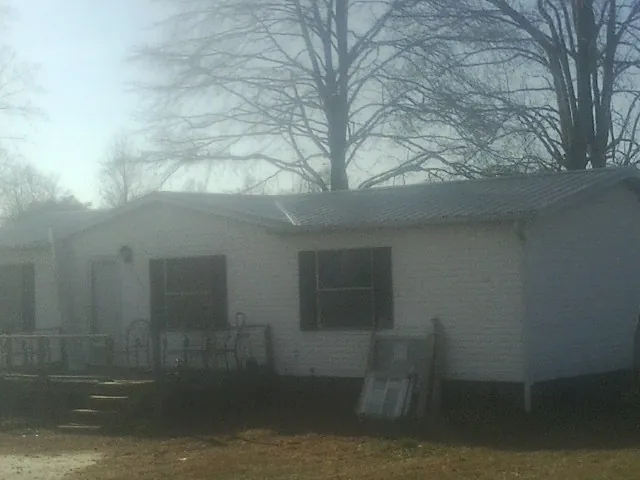 New metal roof on a white painted brick home on a foggy morning in Center