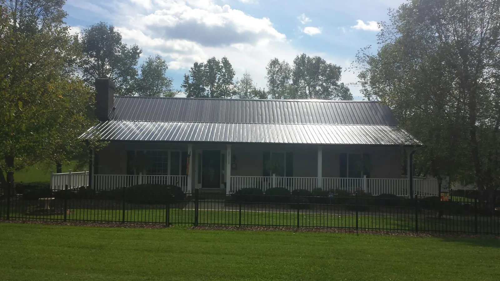 Gray metal roof on a brick ranch with a full width front porch — Gutter Guard Installation work by our crew in Center