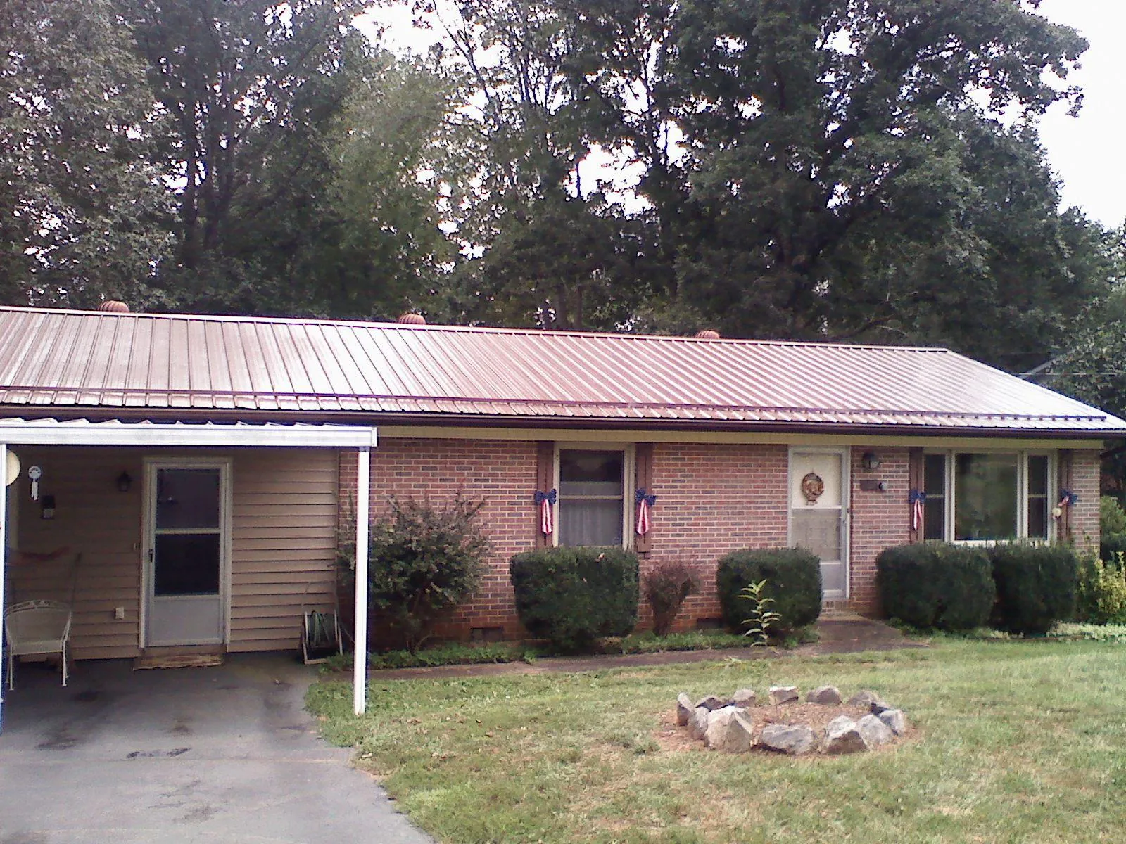 Bronze metal roof and carport on a brick ranch home — Roof Repair work by our crew in Center